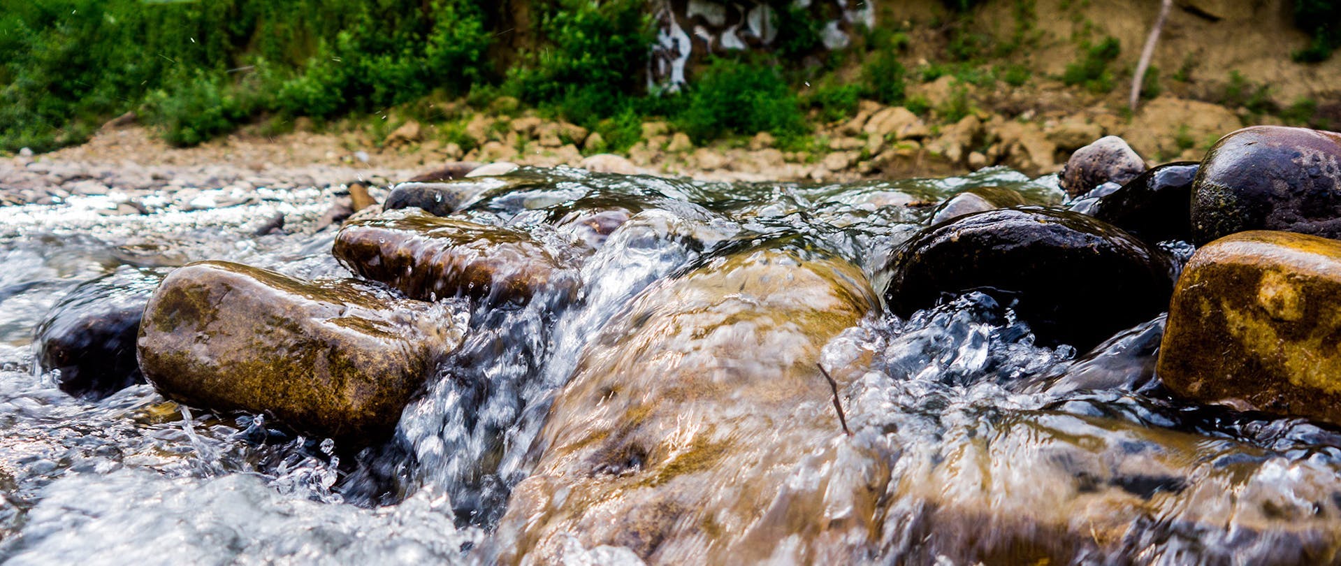 Stream Fresh Water Runs Over Rocks Outside